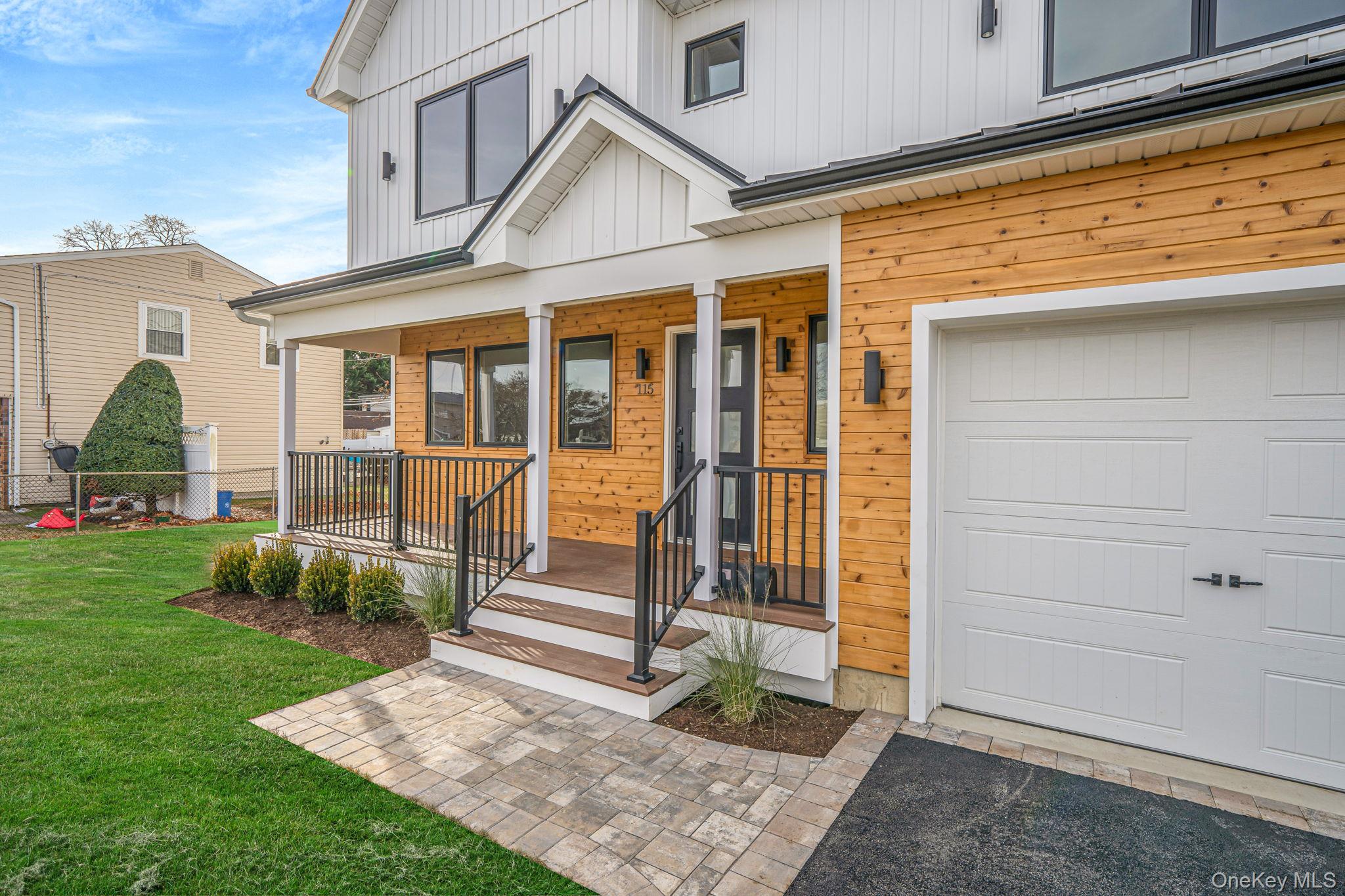 115 Riviera Parkway Lindenhurst, NY 11757 - Photo 4 of 33 Doorway to property with a lawn, a porch, board and batten siding, and a garage