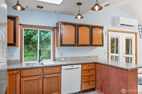 a kitchen with stainless steel appliances granite countertop a stove a sink and a granite counter tops with large windows
