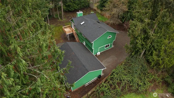 an aerial view of a house with a yard and trees all around