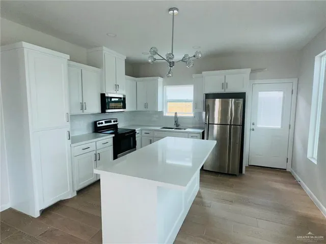 a kitchen with kitchen island a refrigerator sink and cabinets