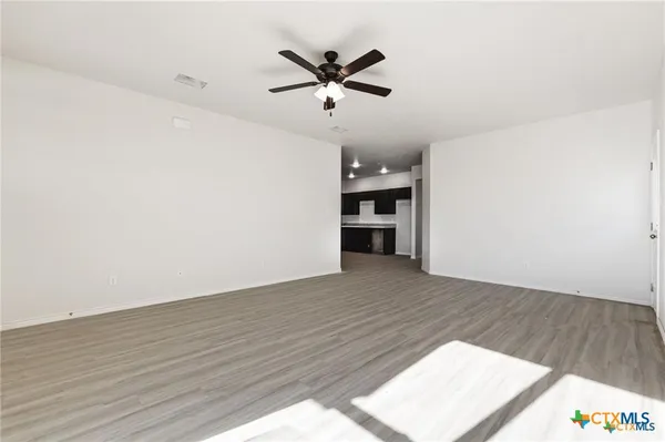 an empty room with wooden floor and ceiling fan