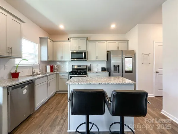a kitchen with kitchen island granite countertop a sink cabinets and stainless steel appliances