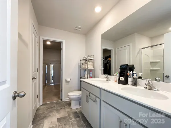 a bathroom with a double vanity sink a toilet and shower