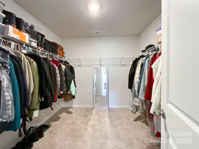 a view of walk in closet with clothes and shoes