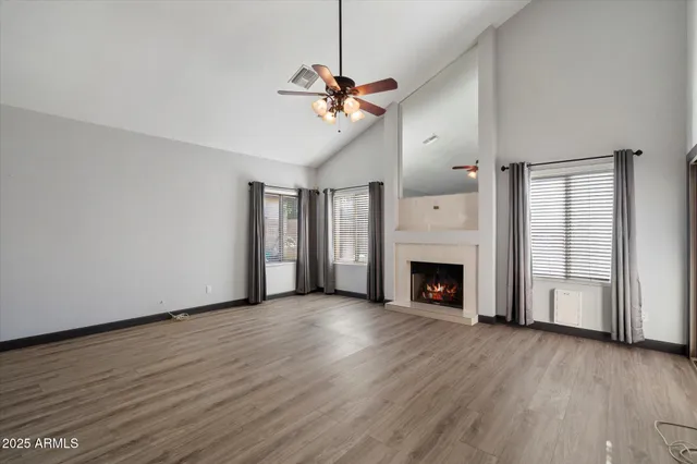 a view of a livingroom with a fireplace chandelier fan and windows