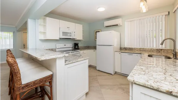a kitchen with granite countertop a sink stainless steel appliances and white cabinets
