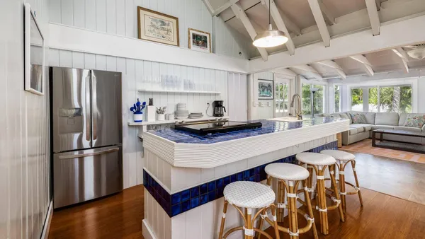 a kitchen with stainless steel appliances granite countertop a refrigerator a sink dishwasher a stove and a dining table with wooden floor