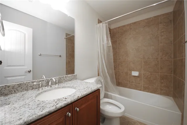 a bathroom with a granite countertop sink a toilet and shower