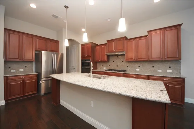 a kitchen with stainless steel appliances granite countertop a sink refrigerator and cabinets