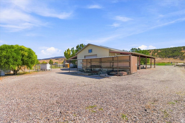 11290 South Southfield Road Mayfield, UT 84643 - Photo 26 of 103 Expansive gravel lot with a large building featuring a roll-up door and an extended covered awning