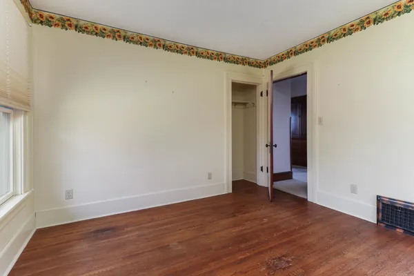 a view of an empty room with wooden floor and a window