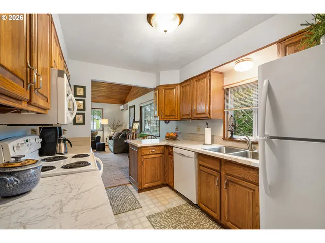 a kitchen with stainless steel appliances granite countertop a stove a sink dishwasher and a refrigerator with wooden cabinets