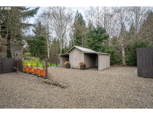 a view of a house with backyard and trees in the background