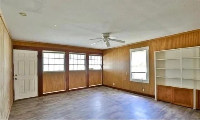 an empty room with wooden floor cabinet and windows
