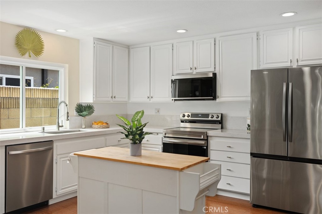 11596 Lakia Drive Cypress, CA 90630 - Photo 12 of 46 a kitchen with stainless steel appliances a sink a stove a refrigerator and cabinets