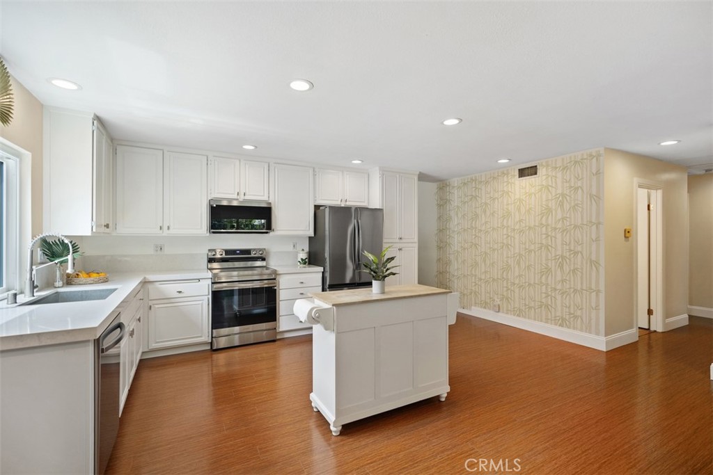 11596 Lakia Drive Cypress, CA 90630 - Photo 14 of 46 a kitchen with a refrigerator a stove top oven a counter space and wooden floor