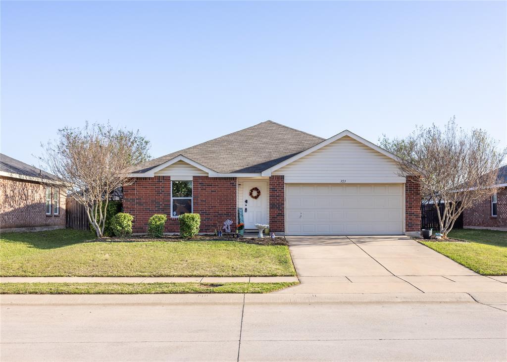 Ranch-style home featuring a front yard, an attached garage, brick siding, and concrete driveway