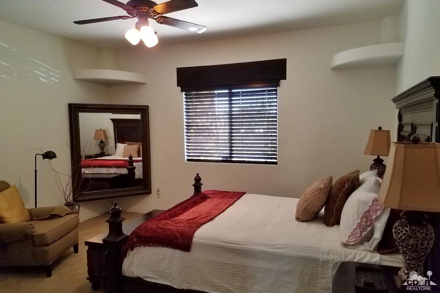 52225 Avenida Obregon La Quinta, CA 92253 - Photo 21 of 34 a bedroom with a bed and a chandelier