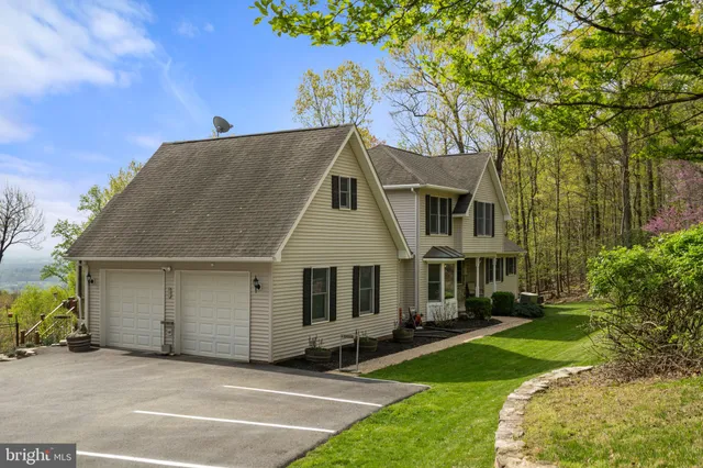 a living room with furniture two large windows and a dining table