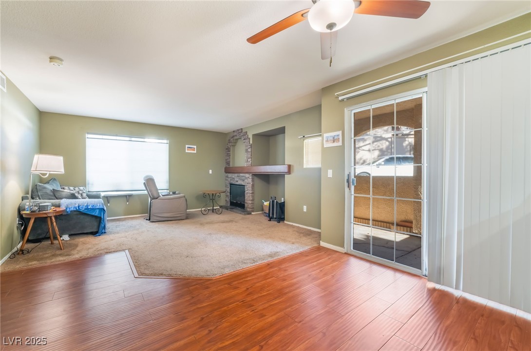 1851 Hillpointe Road, Unit 2912 Henderson, NV 89074 - Photo 11 of 28 Unfurnished living room with ceiling fan, a stone fireplace, wood finished floors, and baseboards