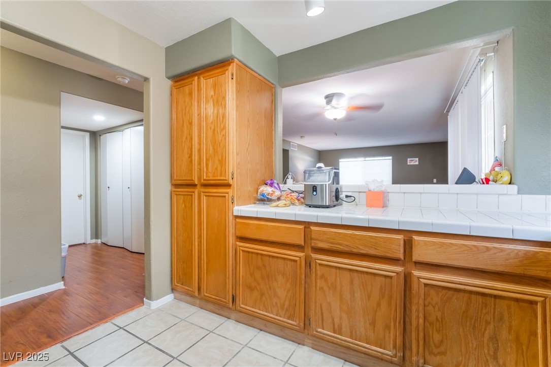 1851 Hillpointe Road, Unit 2912 Henderson, NV 89074 - Photo 8 of 28 Kitchen featuring tile countertops, light tile patterned floors, brown cabinetry, and a ceiling fan