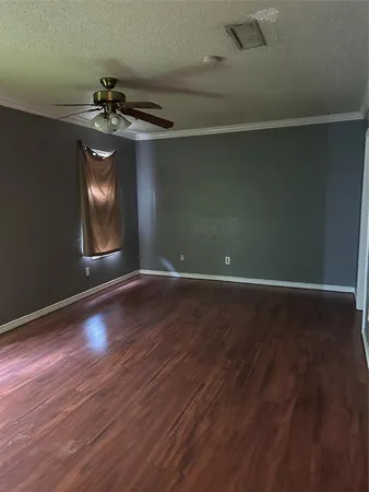 a view of an empty room with wooden floor fireplace and a window