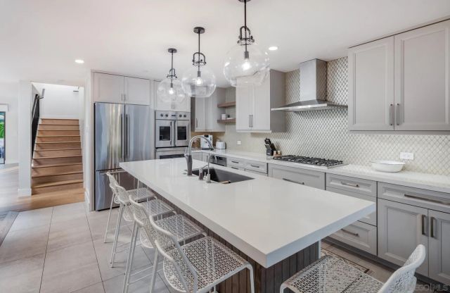 a kitchen with kitchen island a stove a chandelier and a refrigerator