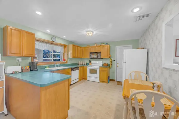a kitchen with a sink dishwasher stove top oven and cabinets with wooden floor