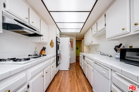 a kitchen with stainless steel appliances granite countertop lots of counter top space and wooden floor