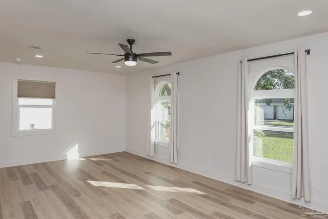 a view of empty room with wooden floor and ceiling fan