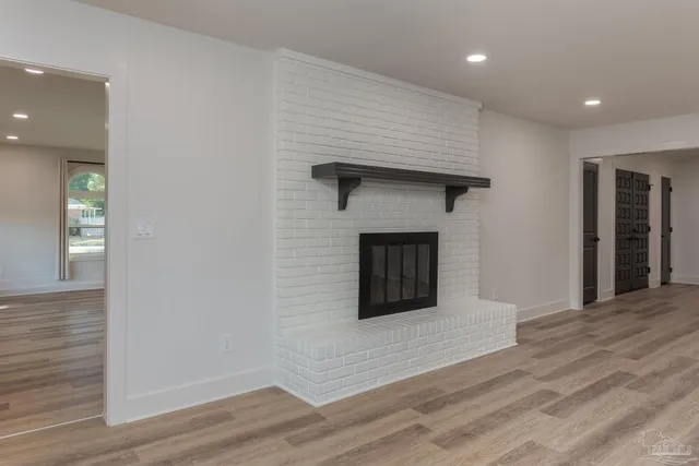 a view of an empty room with wooden floor and a fireplace