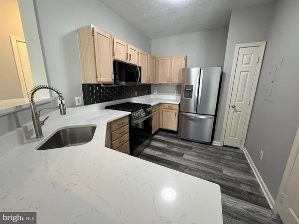 a kitchen with stainless steel appliances a sink a stove a refrigerator a microwave and cabinets