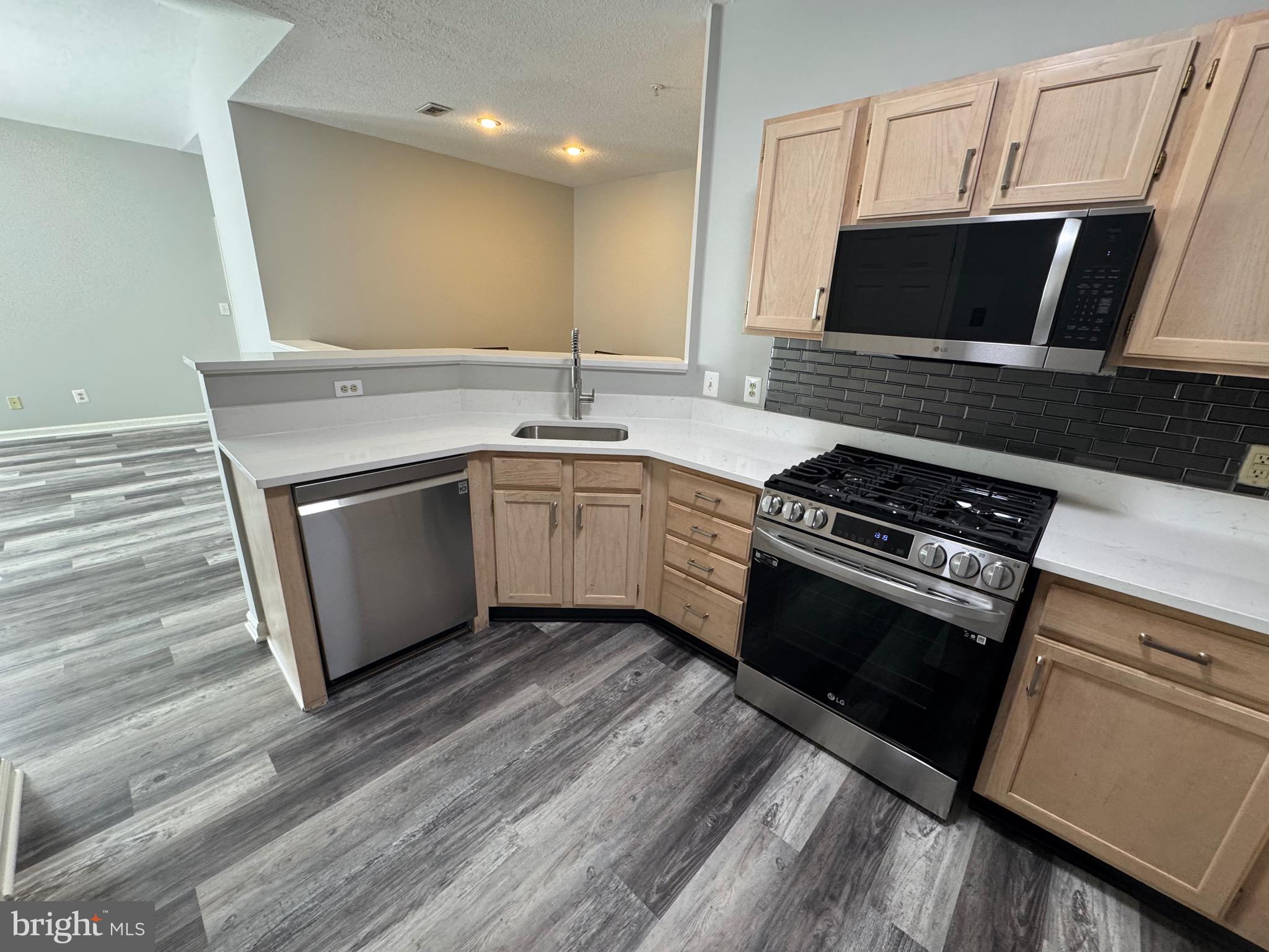 1716 Lake Shore Crest Drive, Unit 32 Reston, VA 20190 - Photo 10 of 40 a kitchen with stainless steel appliances kitchen island granite countertop a stove a microwave and a sink