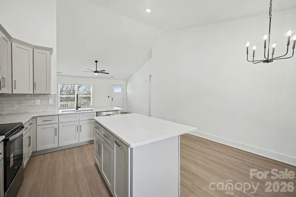 a kitchen with a sink dishwasher and white cabinets with wooden floor