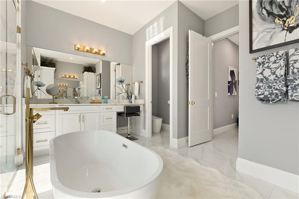 2227 21st Street Southwest Naples, FL 34117 - Photo 26 of 50 a en suite bathroom with a sink a mirror and a bathtub
