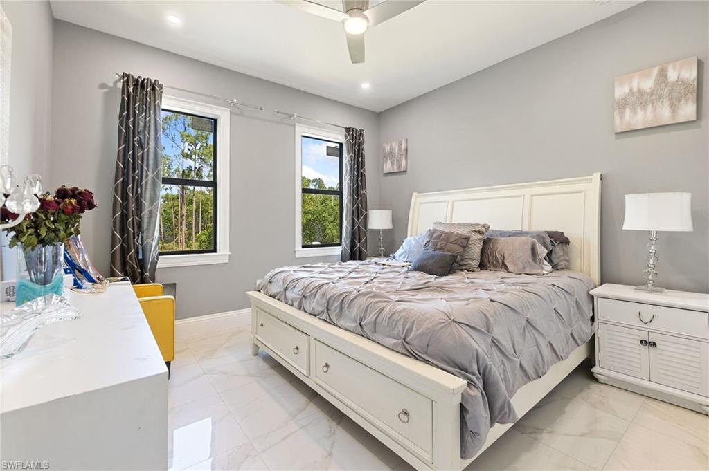 2227 21st Street Southwest Naples, FL 34117 - Photo 35 of 50 a spacious bedroom with a large bed and a chandelier