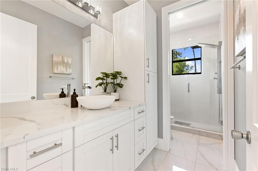 2227 21st Street Southwest Naples, FL 34117 - Photo 36 of 50 a bathroom with a granite countertop sink a mirror and a shower