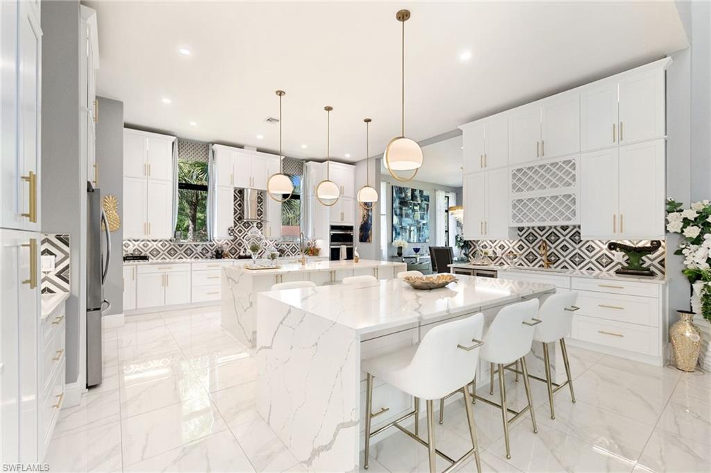2227 21st Street Southwest Naples, FL 34117 - Photo 10 of 50 a large white kitchen with a large island oven a sink stainless steel appliances and cabinets
