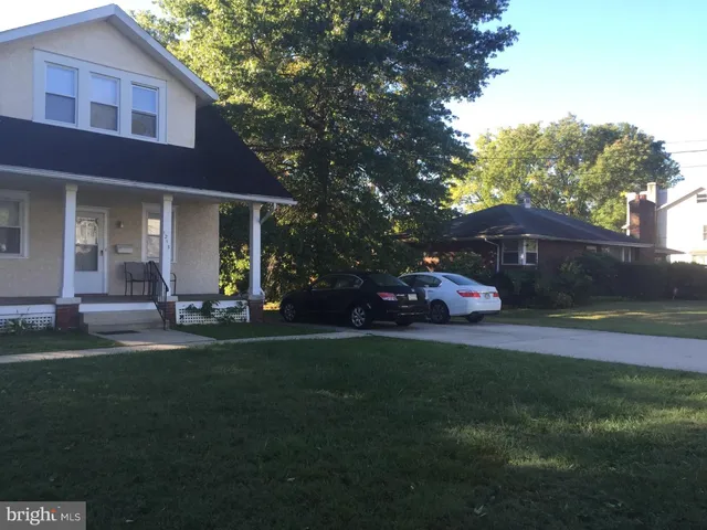 a front view of a house with a garden and trees