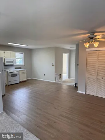 a view of empty room with kitchen and window