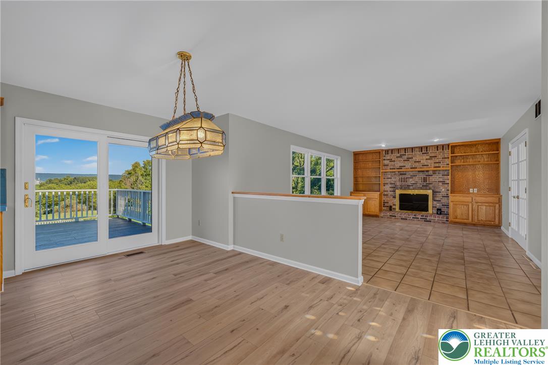 630 Clearfield Road Nazareth, PA 18064 - Photo 100 of 100 An open floor plan connects the dining area to a brick fireplace and adjacent deck.