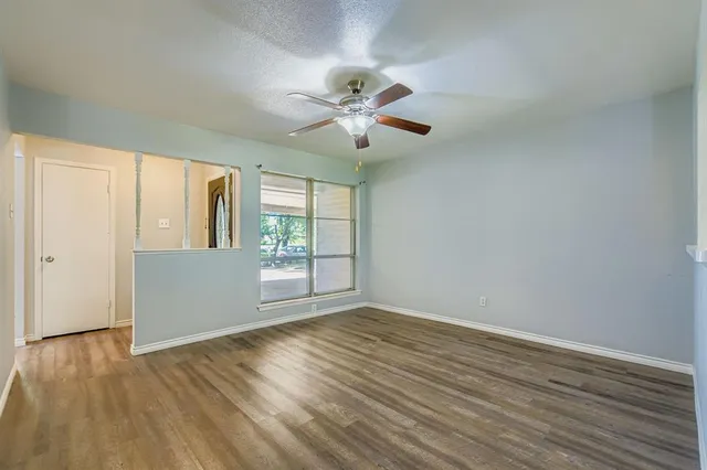 a view of an empty room with a window and wooden floor