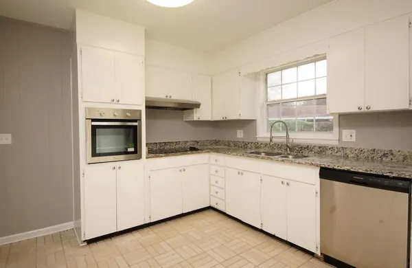 a kitchen with granite countertop white cabinets and a sink