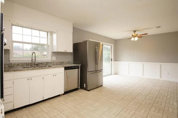 a kitchen with granite countertop a sink cabinets stainless steel appliances and a window