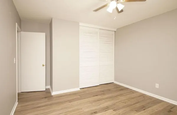 an empty room with wooden floor and fan