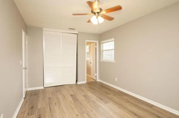an empty room with wooden floor closet and windows
