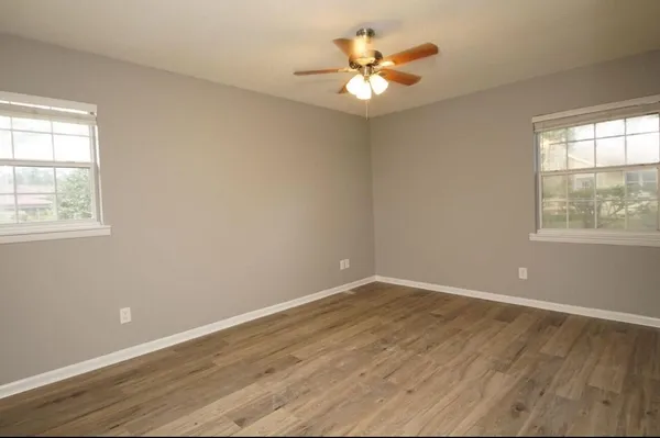 an empty room with wooden floor and windows