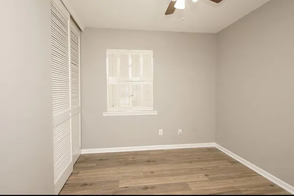 an empty room with wooden floor cabinet and windows