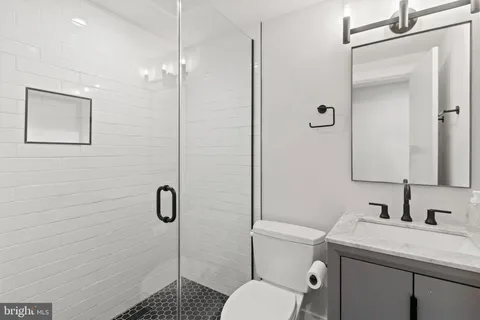 a bathroom with a granite countertop toilet a sink a mirror and shower