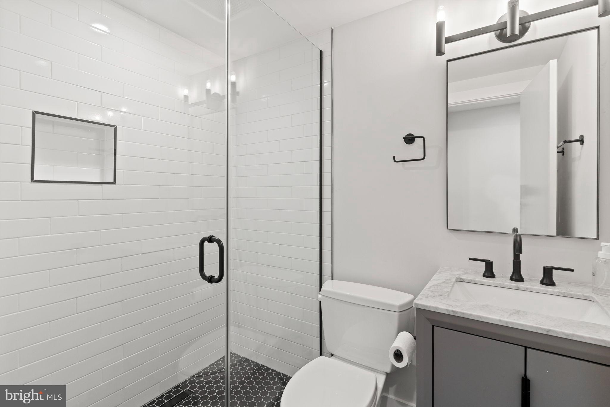 1225 11th Street Northwest, Unit 9 Washington, DC 20001 - Photo 12 of 20 a bathroom with a granite countertop toilet a sink a mirror and shower
